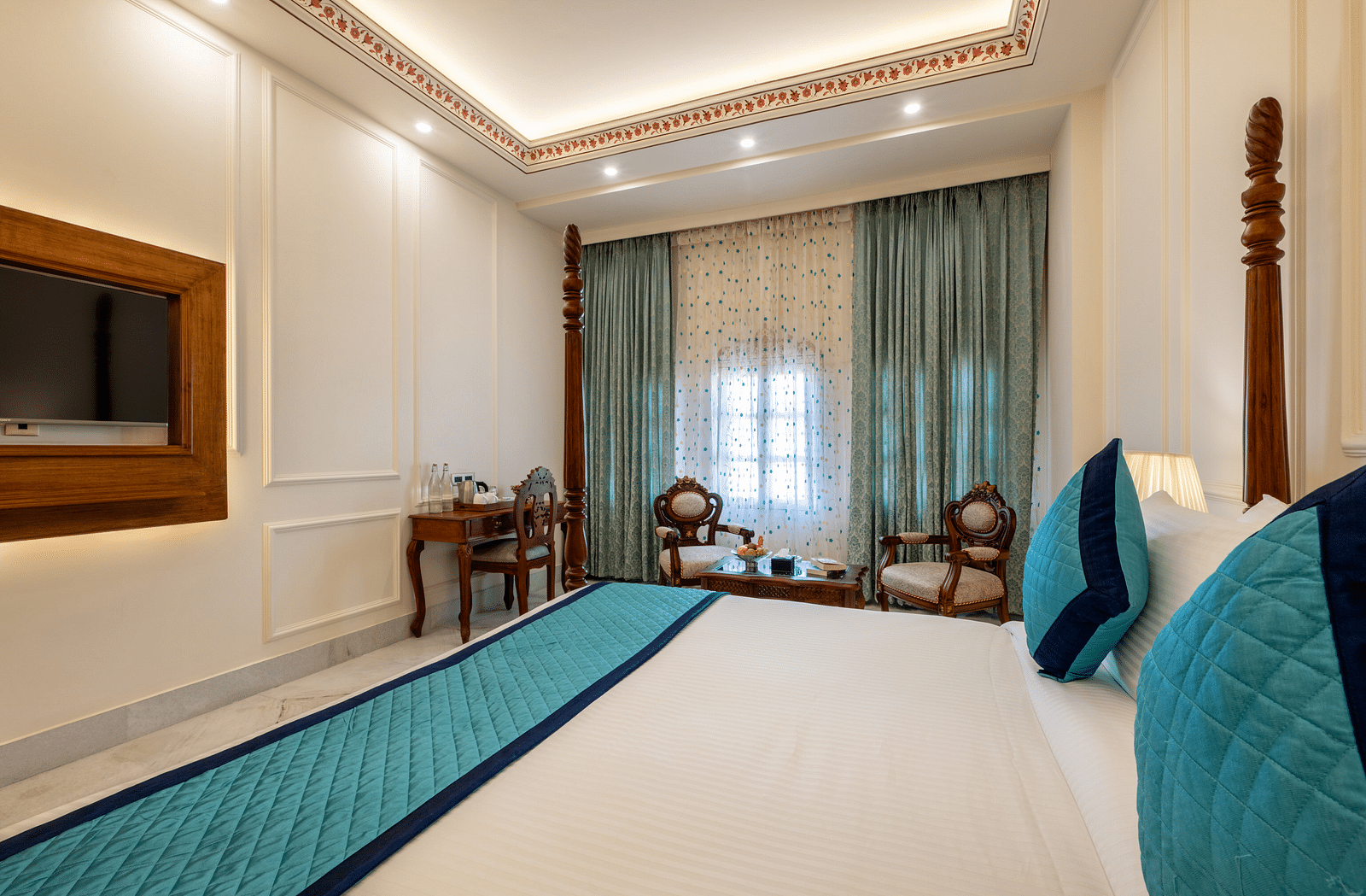 a luxurious bedroom with ample lighting featuring a double bed along with wall mounted television - Brij Castle, Jaipur