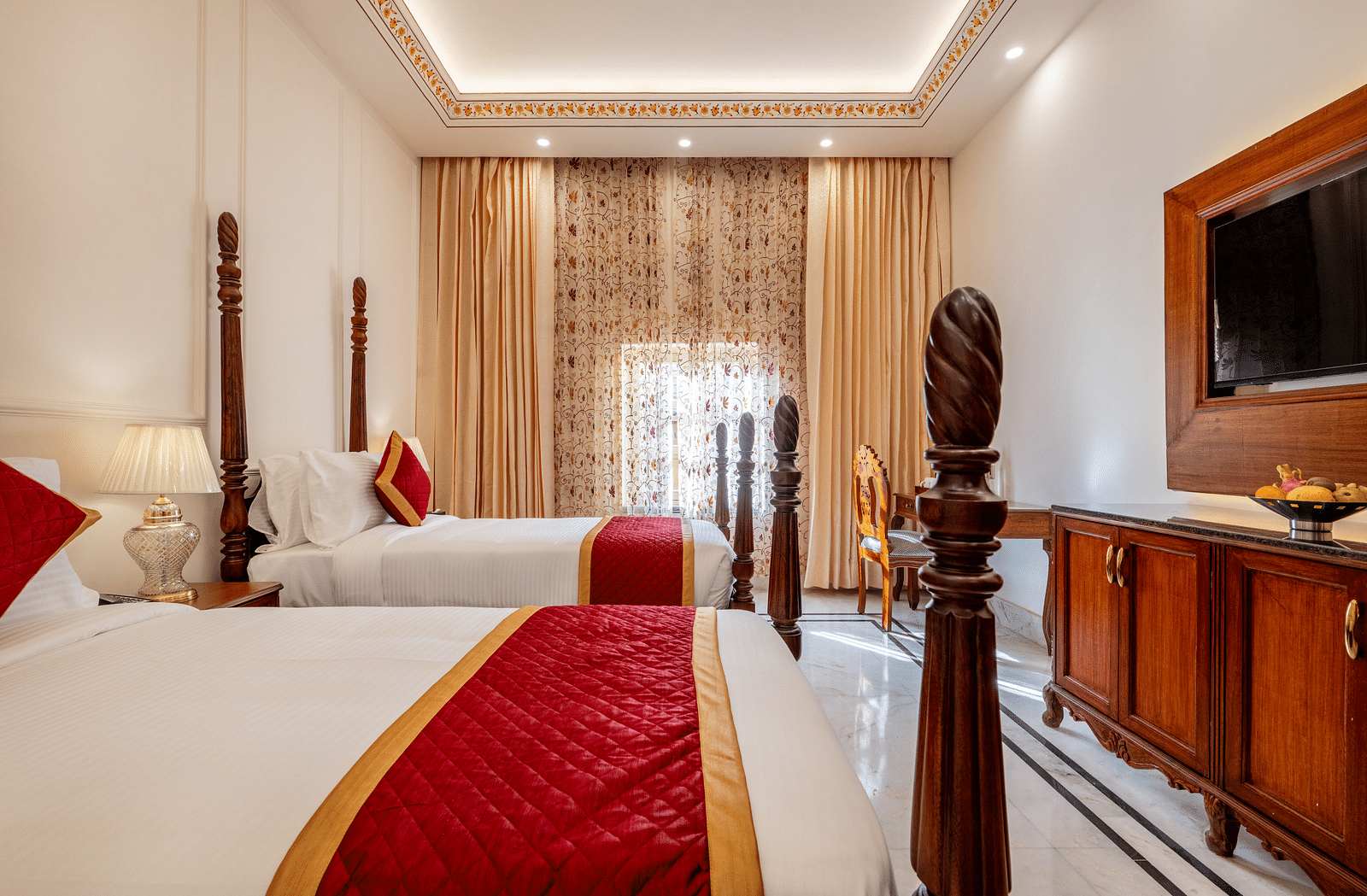 a bedroom with two single beds with a sleek and traditional modern interiors with a wall mounted television in front of it - Brij Castle, Jaipur