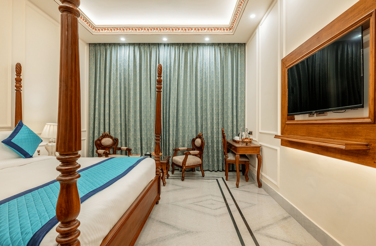 a room with a wall mounted television right opposite to the king size bed - Brij Castle, Jaipur