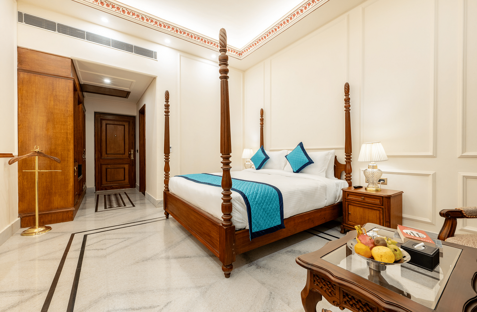 corner view image of the room with a double bed and the wooden door at the entrance crossing the wardrobe - Brij Castle, Jaipur