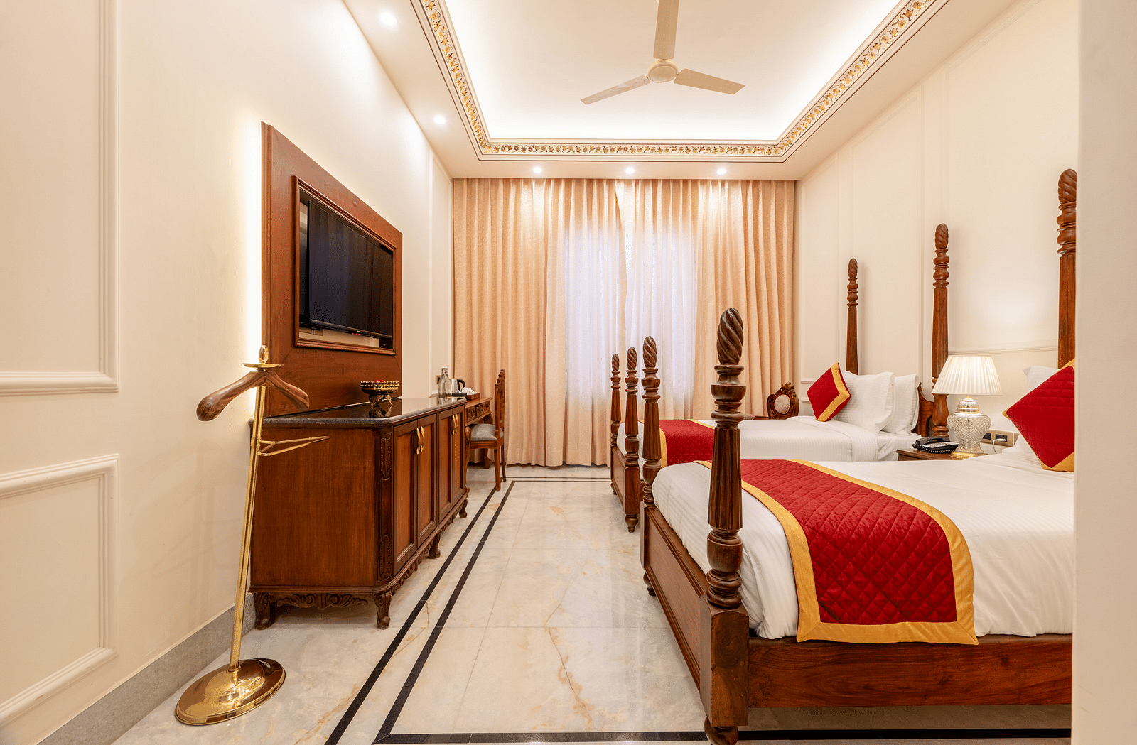 a room with a twin bed facing towards the wall mounted television with a coat hanger beside it - Brij Castle, Jaipur