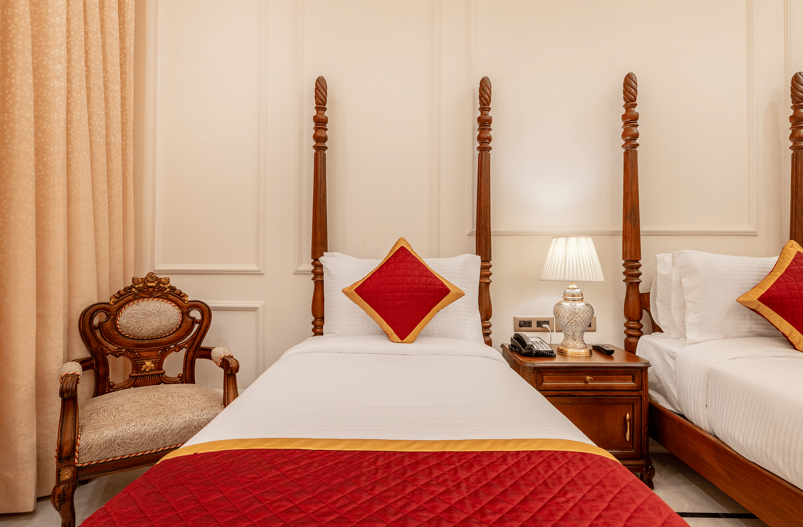 a single bed with a red cushion set against the headboard and an armchair besides it - Brij Castle, Jaipur