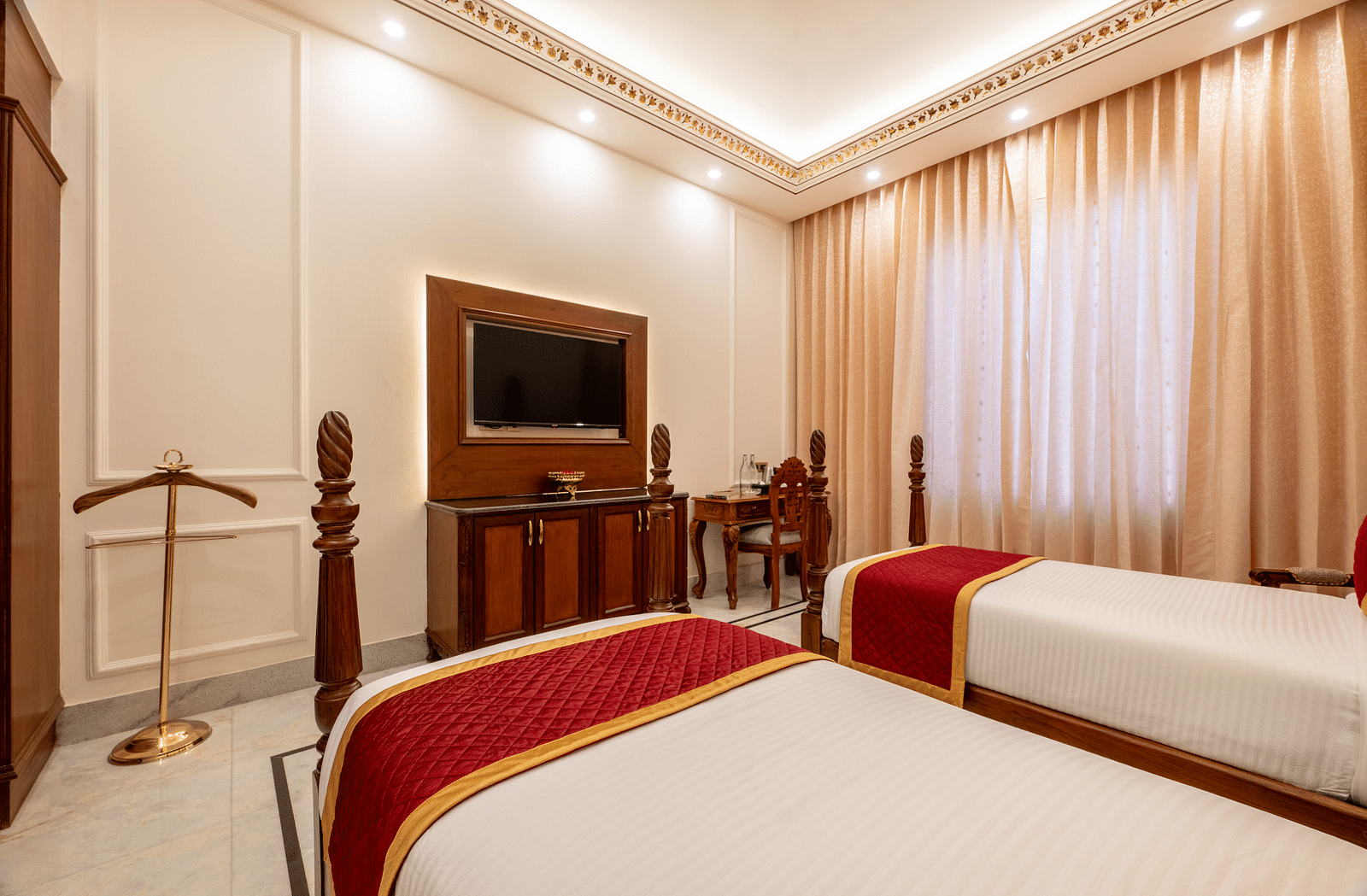 a wall mounted flat television in a bedroom seen over from a twin bed - Brij Castle, Jaipur