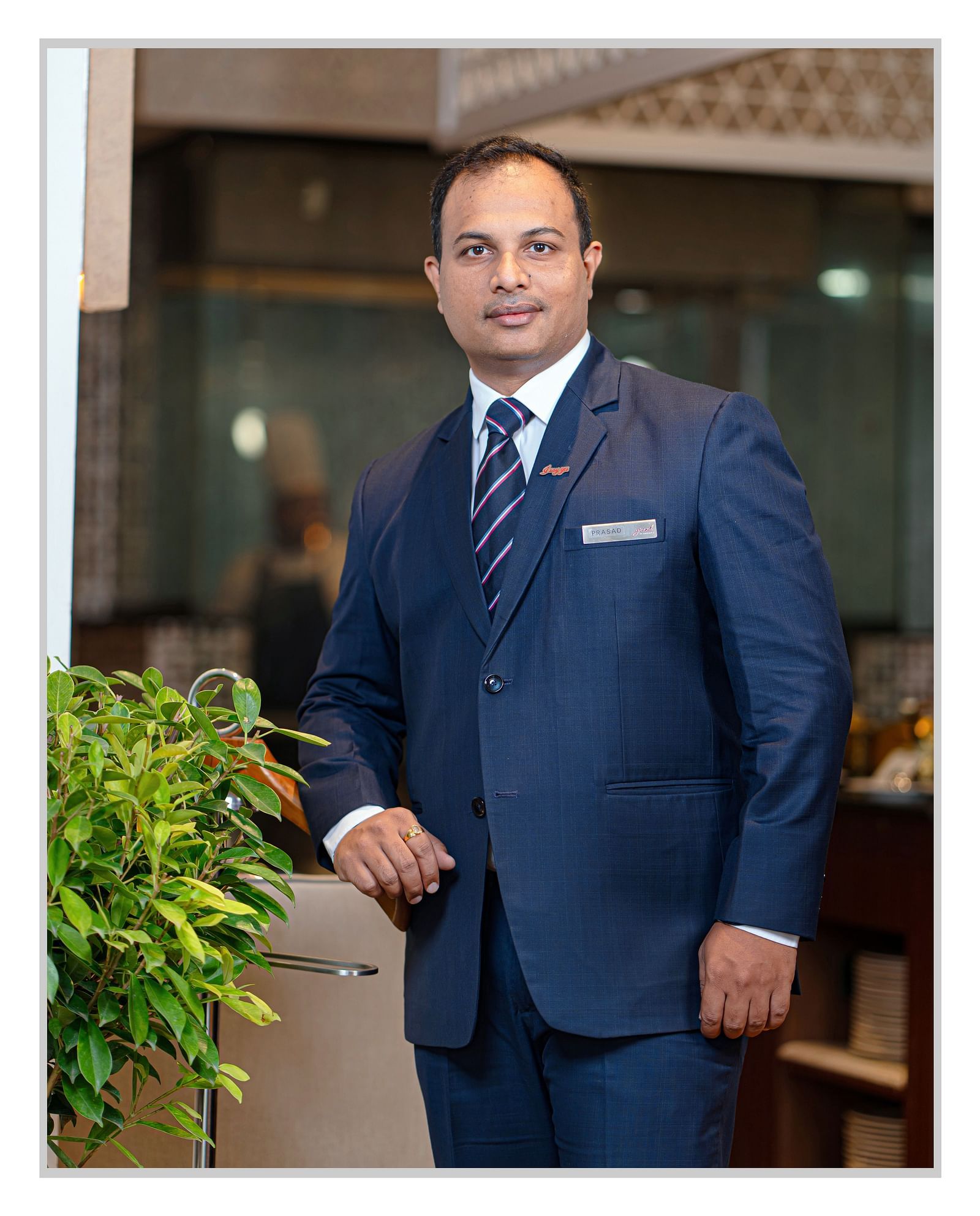 A photo of Mr. Chadalawada Srikanth standing next to a plant.