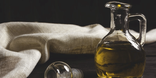 A container of liquid placed beside a small glass resting on fabric