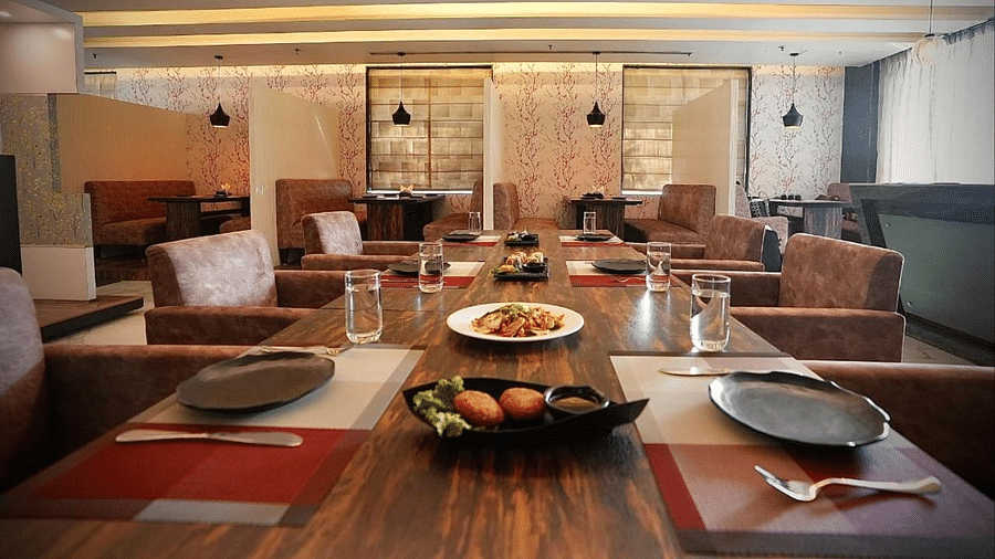 A restaurant with set tables, plates, and hanging lights, creating a ready-to-dine atmosphere - VITS Gurugram