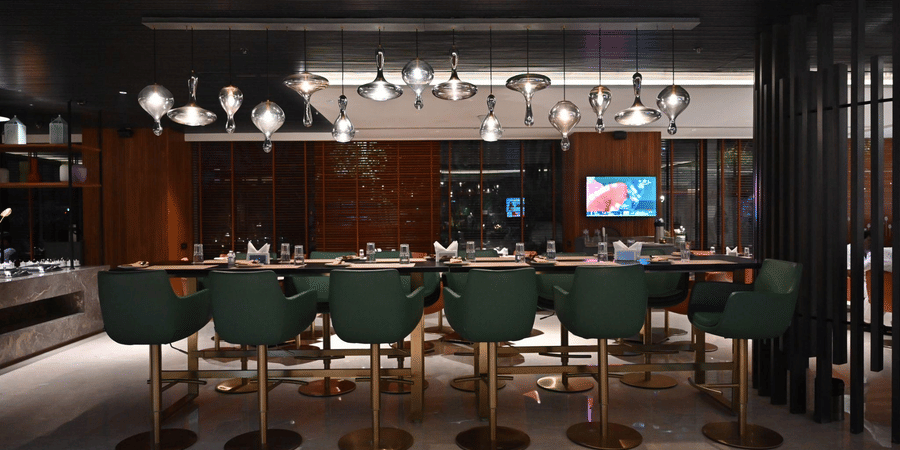 A sleek bar lounge featuring green bar stools and ambient lighting, designed for upscale dining and drinks.