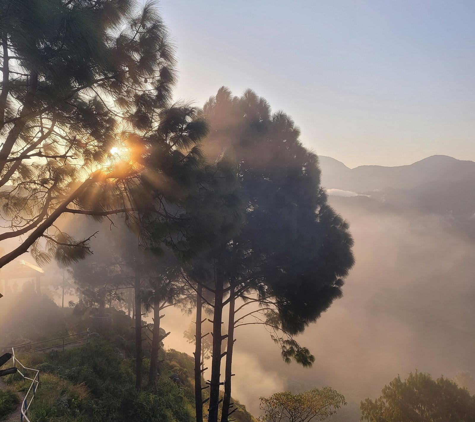 An overview of Bandipur in Nepal with mist covering the trees and the sun rising.
