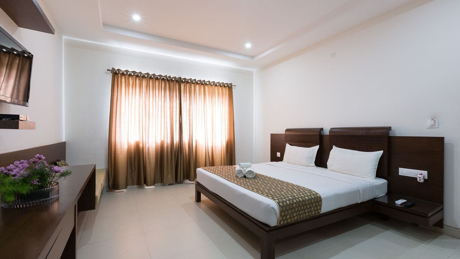 A bedroom with a bed, wooden furniture, and neutral-toned decor under soft lighting - Sanctum Suites BEL Road, Bangalore