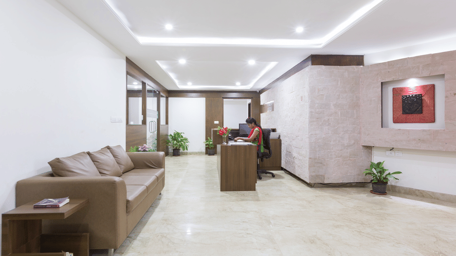 A modern hotel lobby with marble flooring, sofa seating and recessed lighting