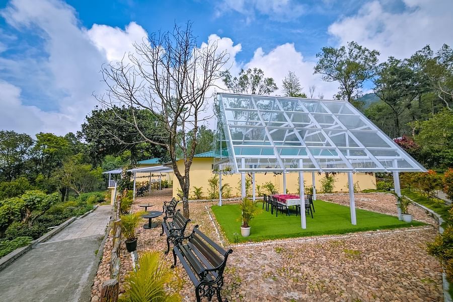 an image of side view of outdoor seating space covered by a glass roof at Ibex Stays & Trails, Valparai (Mistly)