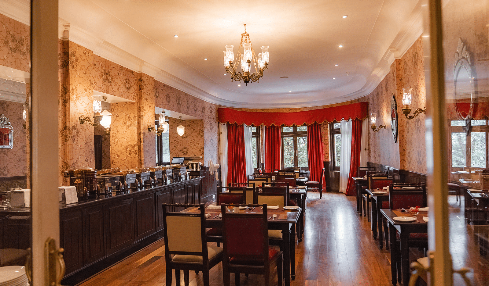 A grand dining room with chandeliers and neatly set tables, offering a luxurious atmosphere for guests.