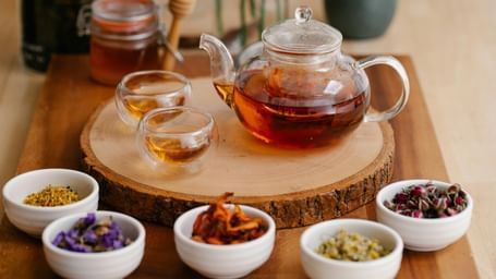 Glass teapot with herbal tea and assorted bowls of dried ingredients on a wooden tray at The Chamomile Estate.