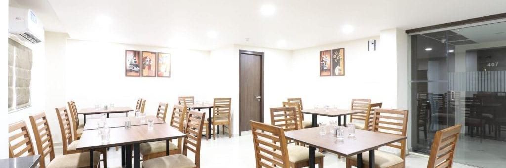 The interiors of Aranaya Restaurant at Pravasa Stay, Ahmedabad (Alba Premier), featuring well-arranged dining tables.