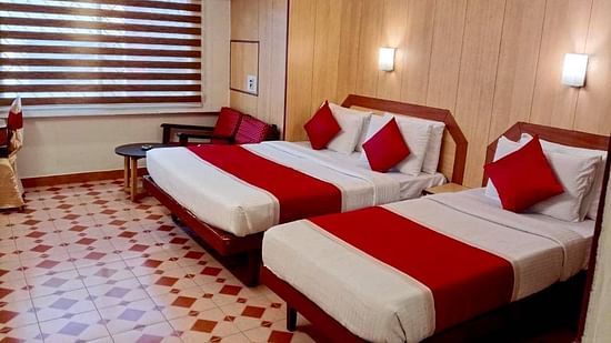 Room with a single bed, a double bed, and a seating area at Hotel Swagath, Bangalore