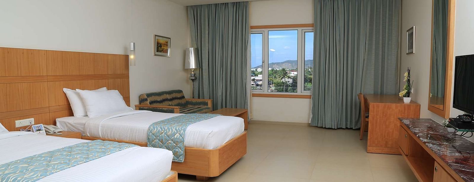 A spacious twin-bedroom setup with a contemporary design, large windows, and modern amenities.- Dhanalakshmi Srinivasan Hotels, Perambalur