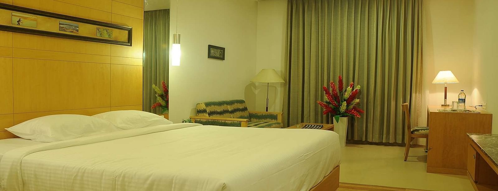 A cosy hotel room with a plush queen-sized bed, warm lighting, and soft furnishings for ultimate relaxation.- Dhanalakshmi Srinivasan Hotels, Perambalur