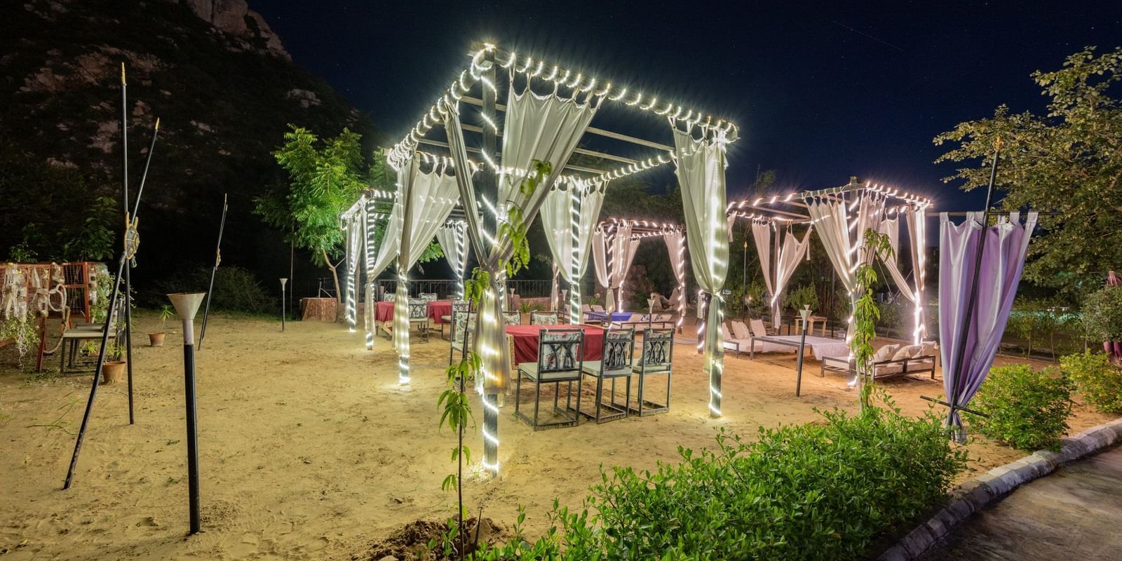 Night view of an open dining space decorated with sheer curtains and lights at Valley by Grassfield.