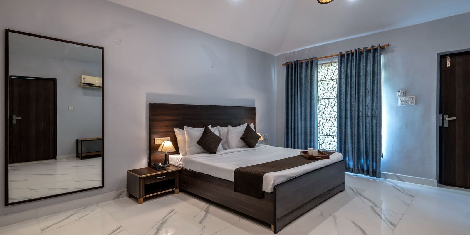 Side view of a room with a bed and a large mirror beside it at Valley by Grassfield.