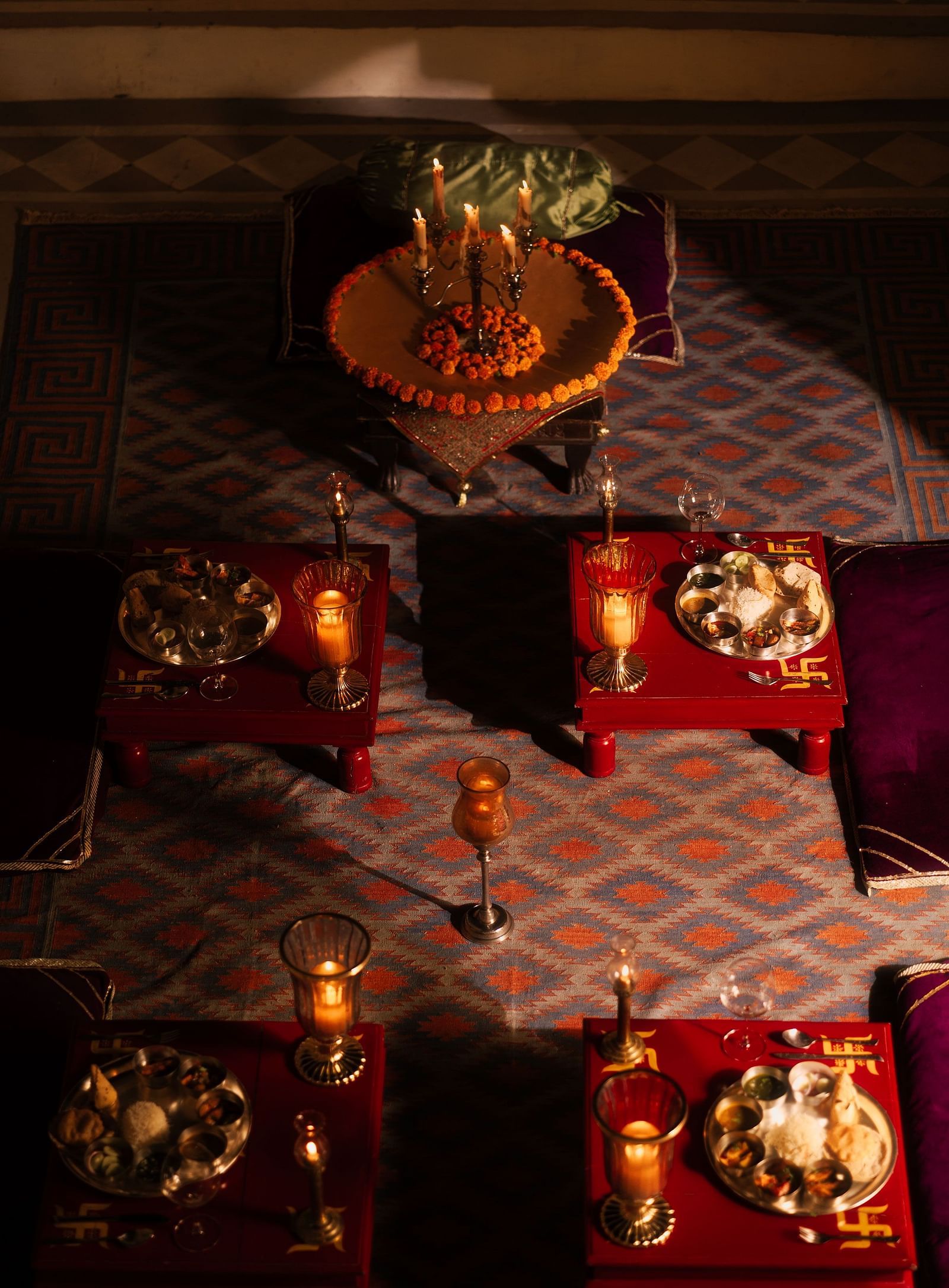An overhead view of a richly decorated seating area at Fort Barli, featuring low tables with ornate details and plush cushions.
