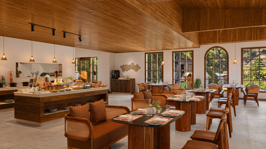 Indoor restaurant seating area with wooden tables, chairs, and warm contemporary interior design.