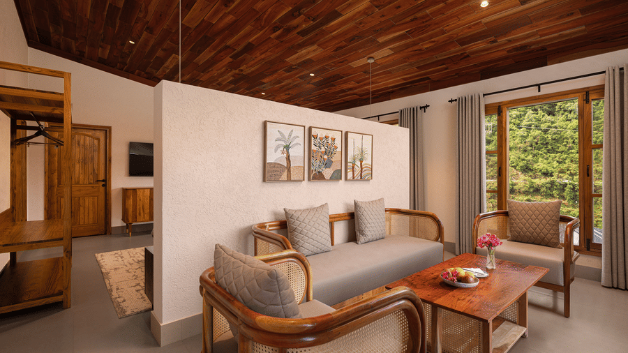 Elegant resort suite living area with a wooden ceiling, cozy sofa seating, and large windows looking out to greenery.