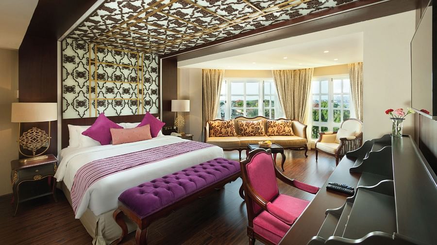 Spacious room with a decorative headboard extending across the ceiling and a large window partially covered by a curtain