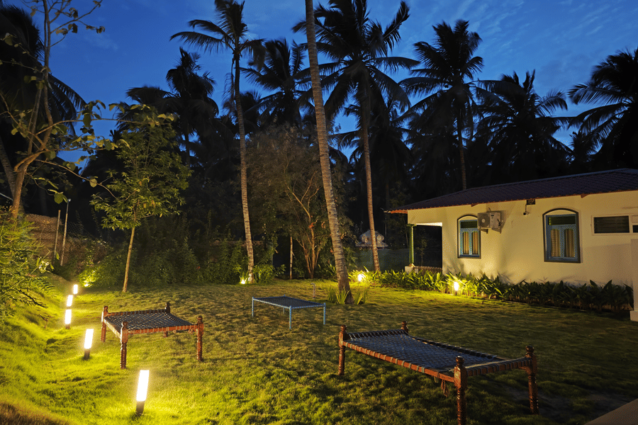 Illuminated garden pathway at Ibex Resorts, Coimbatore (Kakarla), surrounded by lush greenery and cottages, creating a serene ambience for evening stays and events.