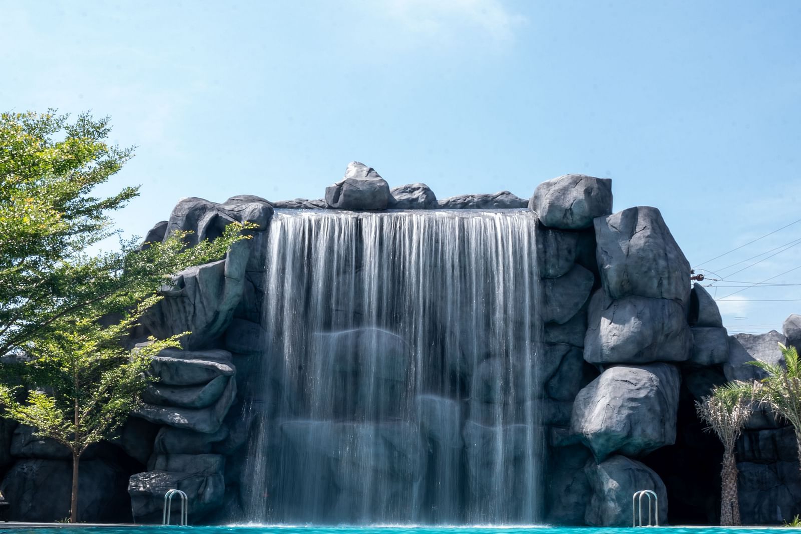 A wide-angle view showcasing a stunning waterfall-like structure with a pool in front, creating the perfect setting for family fun activities.