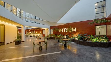 A modern outdoor seating area with a large, red 'ATRIUM' sign on the wall.  - The Pelican Hotel, Accra
