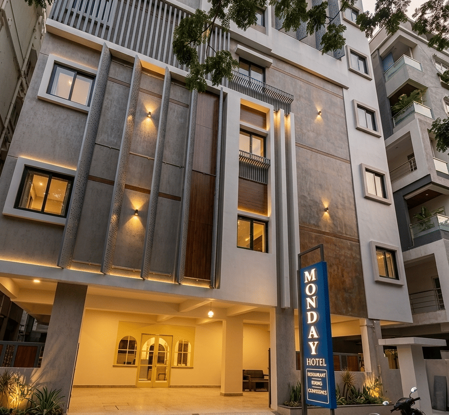 Illuminated facade with sign board, lights, and trees. | Monday Hotels Ayyappa Society Madhapur Hyderabad