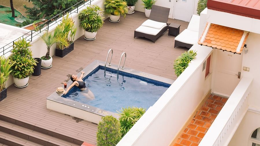An aerial view shows multiple buildings with orange-tiled roofs and a swimming pool surrounded by trees and greenery | Central Mansions, Phnom Penh