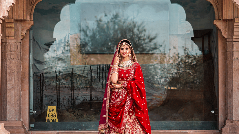 a bride posing for a picture below an arch of a building 