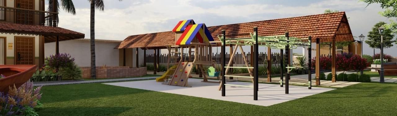 A grassy outdoor area with playground equipment and a building with a brown roof in the background, surrounded by trees and foliage.