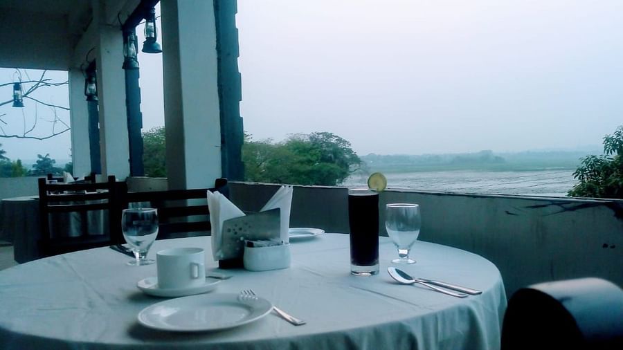 A dining space with an outdoor view featuring a round table covered in white table cloth and set with plates