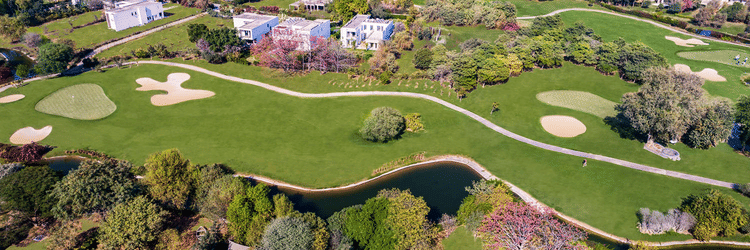 aerial view of Karma Lakelands with a golf course, buildings and trees in view.