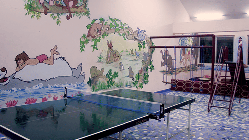 A games area at the best resort in Bangalore, with a table tennis table and a mural on the wall | Ramanashree California Resort