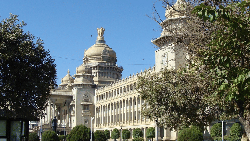 A grand, multi-storey stone building featuring ornate domes and columns, surrounded by manicured trees.