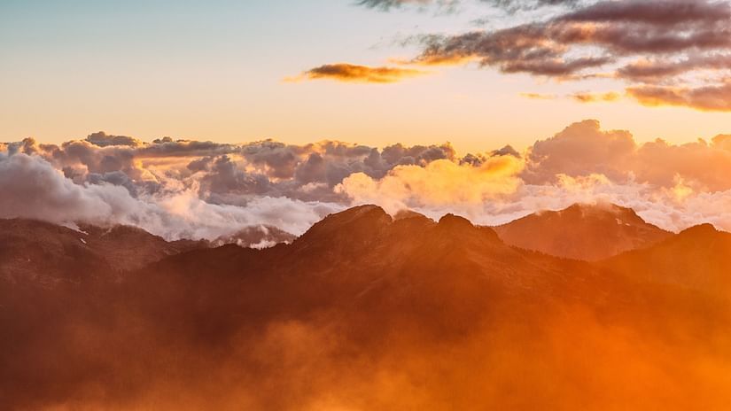 a beautiful golden hour of the day captured around mountains covered with soft white clouds shot during sunset