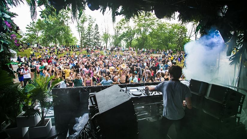 A music festival with a DJ playing music during day time.