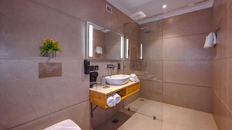 A washroom with a sink, a mirror and a western toilet- Royale Sarovar Portico, Agra