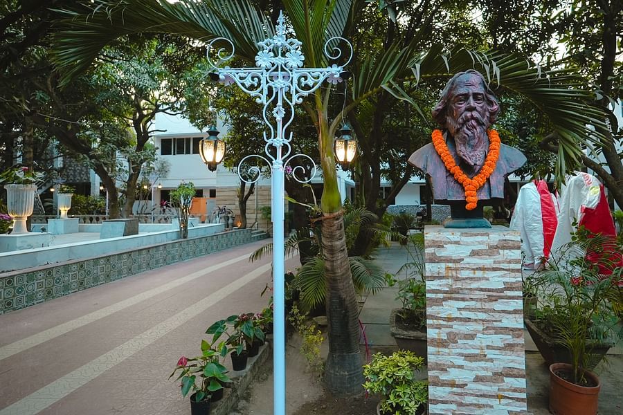An image of a pathway surrounded by trees and on the side there s a lamp stand and a statue at Rangamati Garden Resort