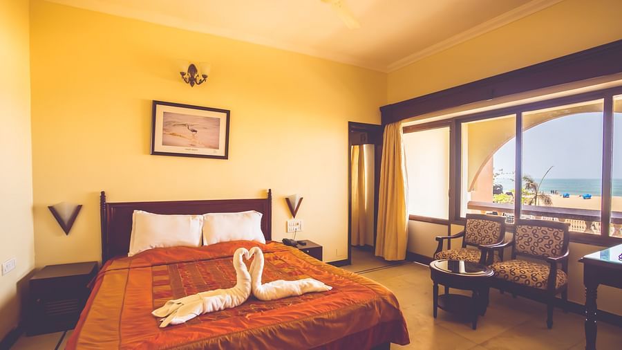 A room at Paradise Isle Beach Resort, Udupi with a double bed, seating arrangement and views of the sea from the window