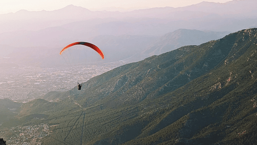 a person paragliding amidst the mountains