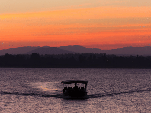 A twilight view of a boat travelling towards the camera with different hues in the sky after the sunset.