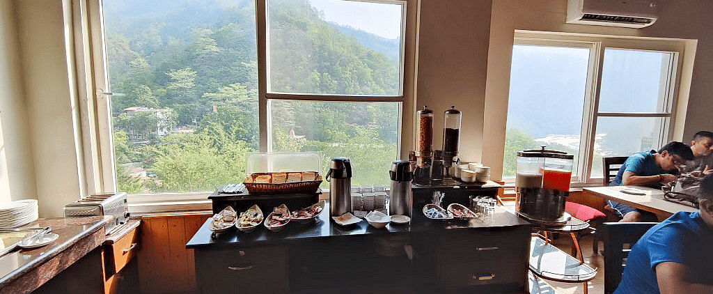 A wooden table with several bowls and tea and coffee flasks kept on it at Regenta Inn DLS.