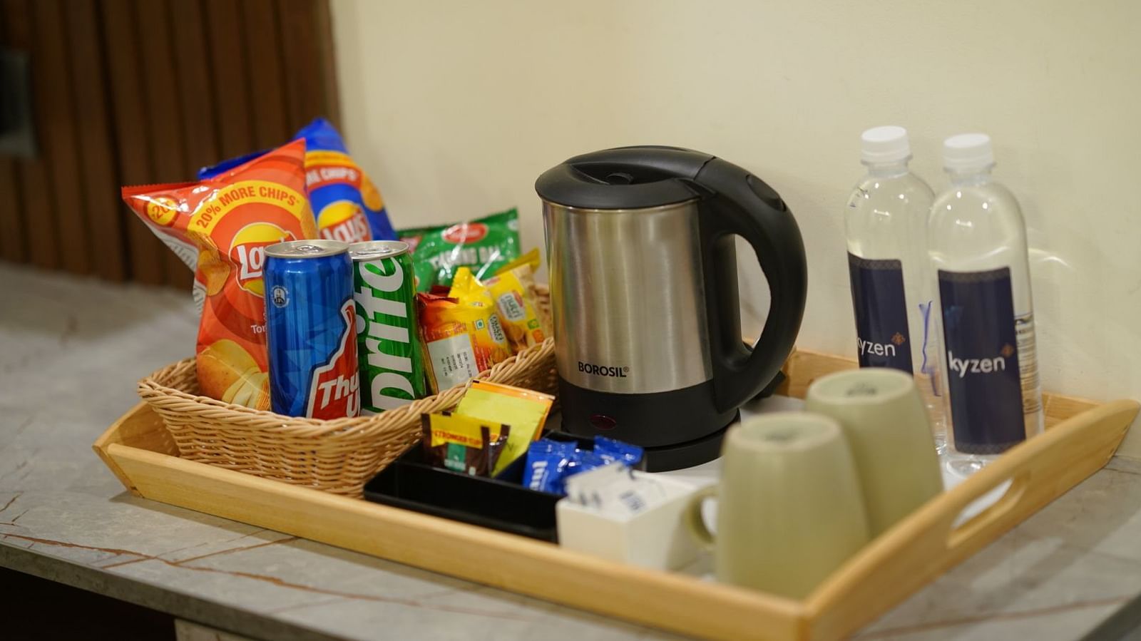 A hospitality tray with snacks, a kettle, and water bottles arranged neatly for guests at Hotel Kyzen Smartstays – Smart, Reliable, Kyzen