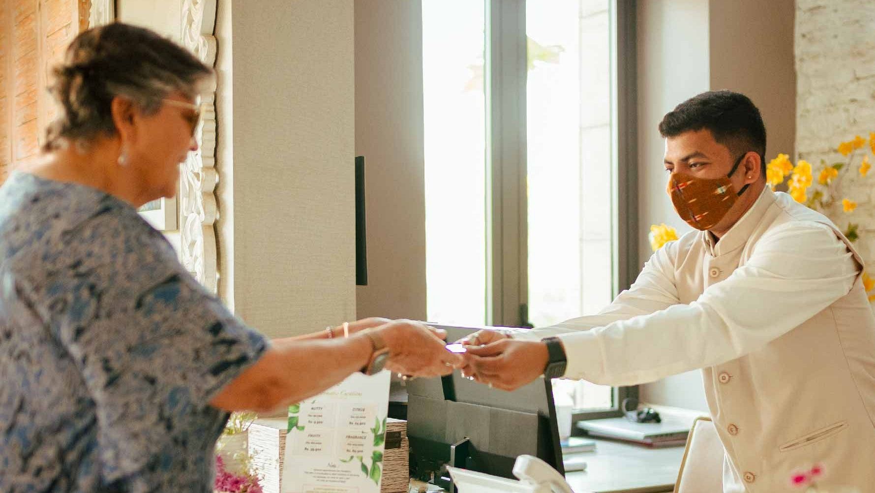 A man offering a visiting card to an elderly woman at Karma Chalets.
