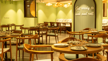 Restaurant seating area with wooden tables and chairs at OJ Japanese, Featherlite Evoma Hotel.