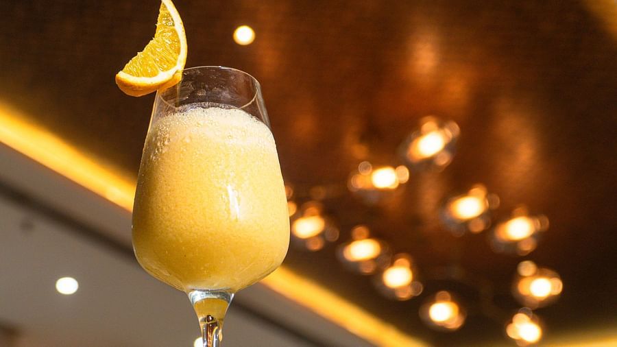 A tall glass filled with a light-colored beverage and garnished with a fruit slice.